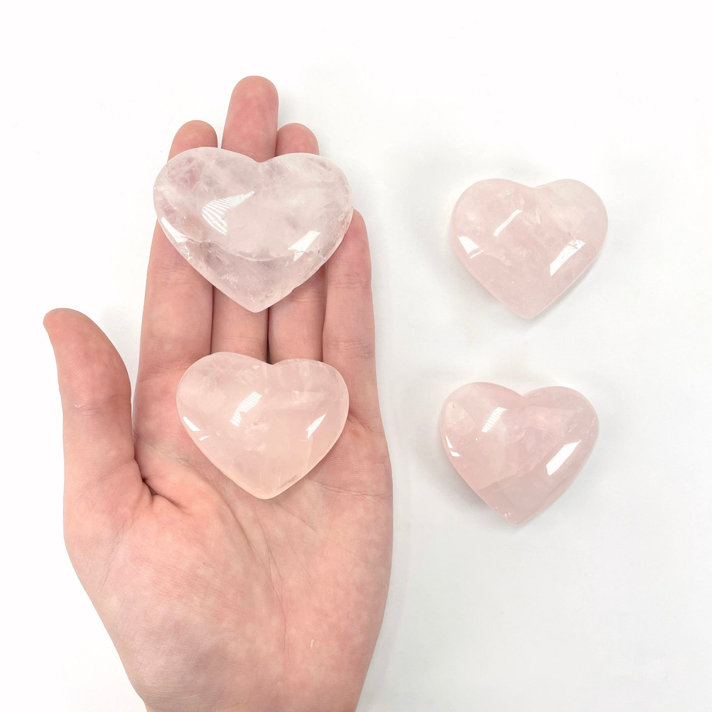 rose quartz polished hearts in hand and on display