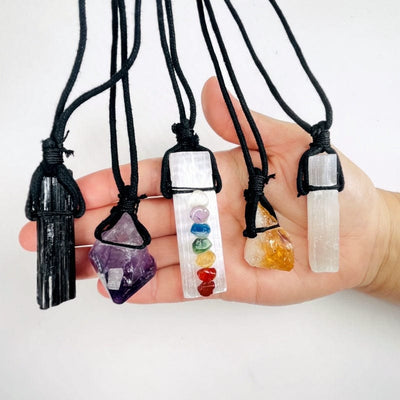 multiple crystal black cord necklaces in hand for size reference 