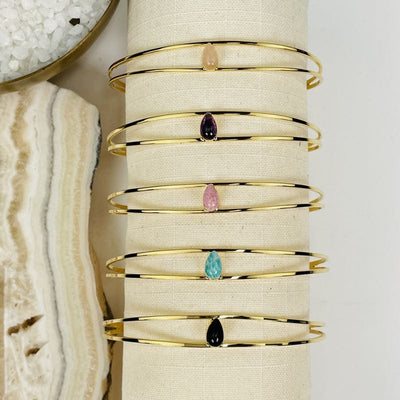 close up of all the droplet bracelets in gold 