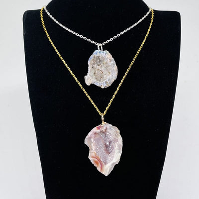 geode half pendants with an angel aura coating and an electroplated silver or gold bail displayed hanging on a chin 