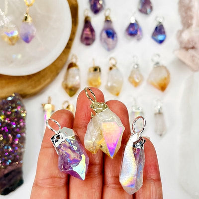 angel aura crystal point pendants in hand for size reference 