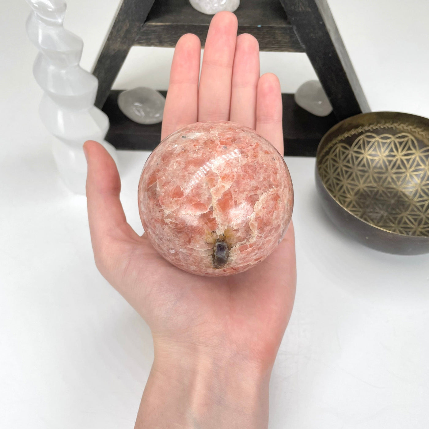 sunstone polished sphere in hand for size reference