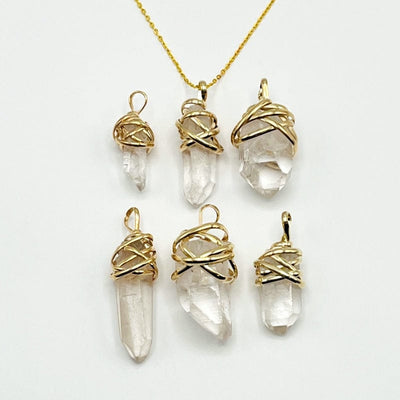 crystal quartz point pendants with thick gold wire wrapped cap and bail displayed to show the differences 