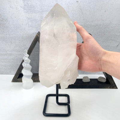 crystal quartz semi-polished point on metal stand in hand for size reference