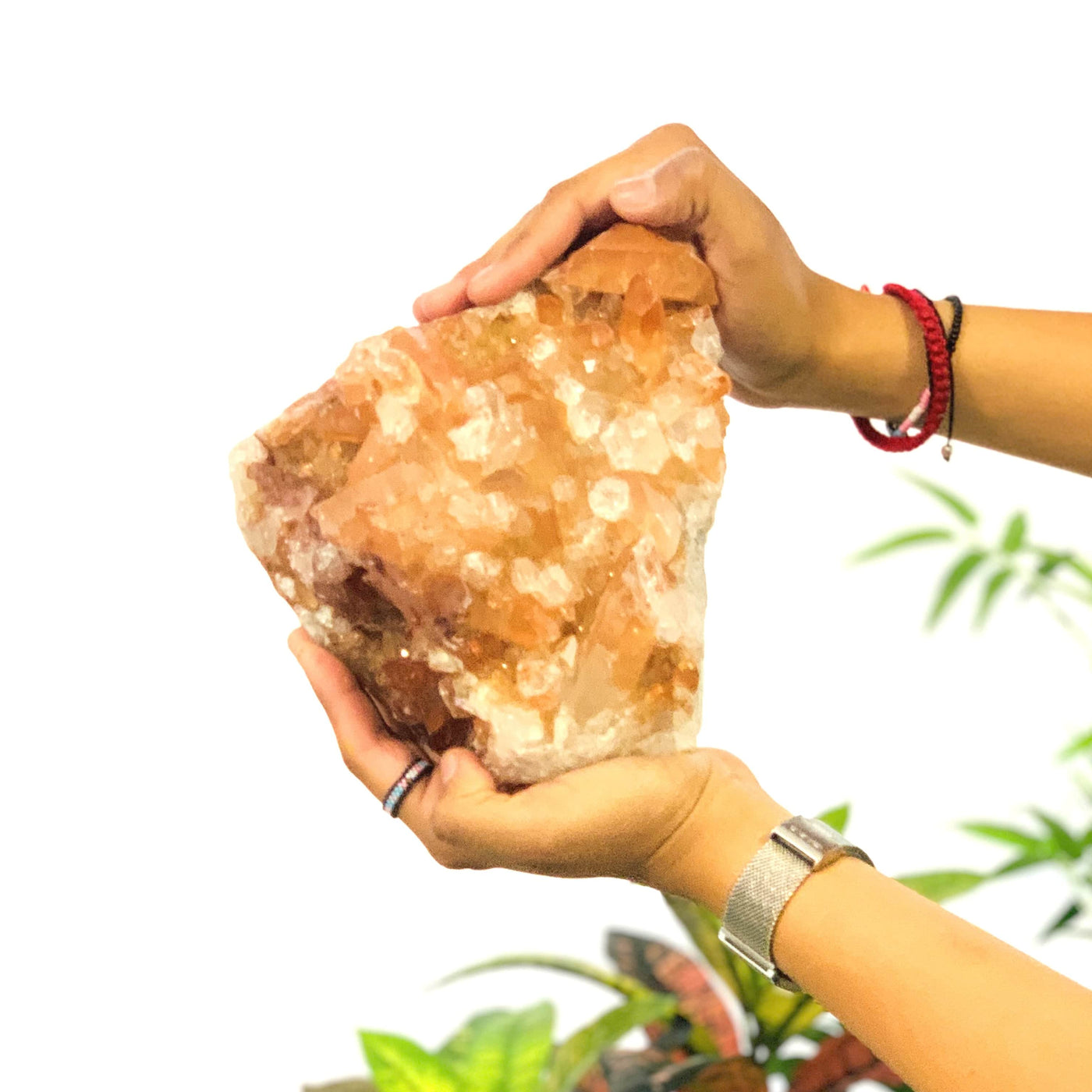 Two hands holding up the frontside of the Tangerine Quartz Cluster