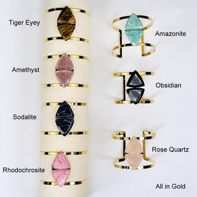 close up of all the gold cuff bracelets showing the different gemstones . available in tiger eye, amethyst, sodalite, rhodochrosite, amazonite, obsidian, and rose quartz