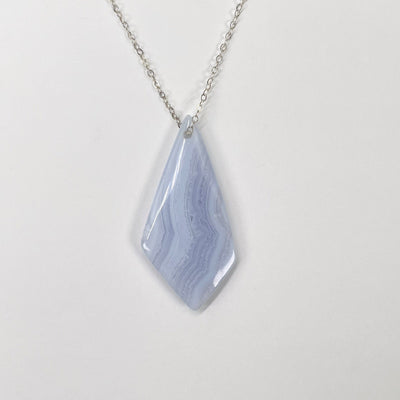 close up of blue lace agate polished diamond pendant strung up on chain