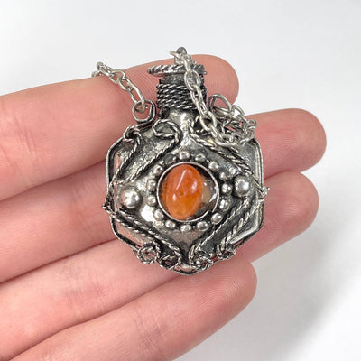 close up of carnelian bottle pendant necklace in hand for size reference and details