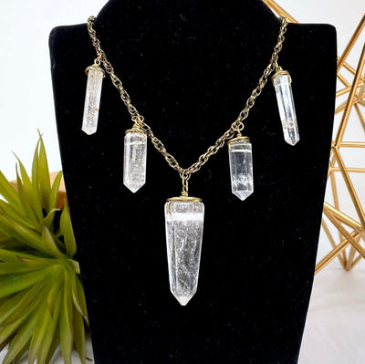 close up of crystal quartz point five pendant necklace on bust display for details