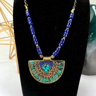 close up of tibetan style pendant necklace with blue beading on busy display for details