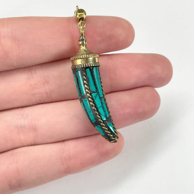close up of turquoise horn pendant in hand for size reference and details