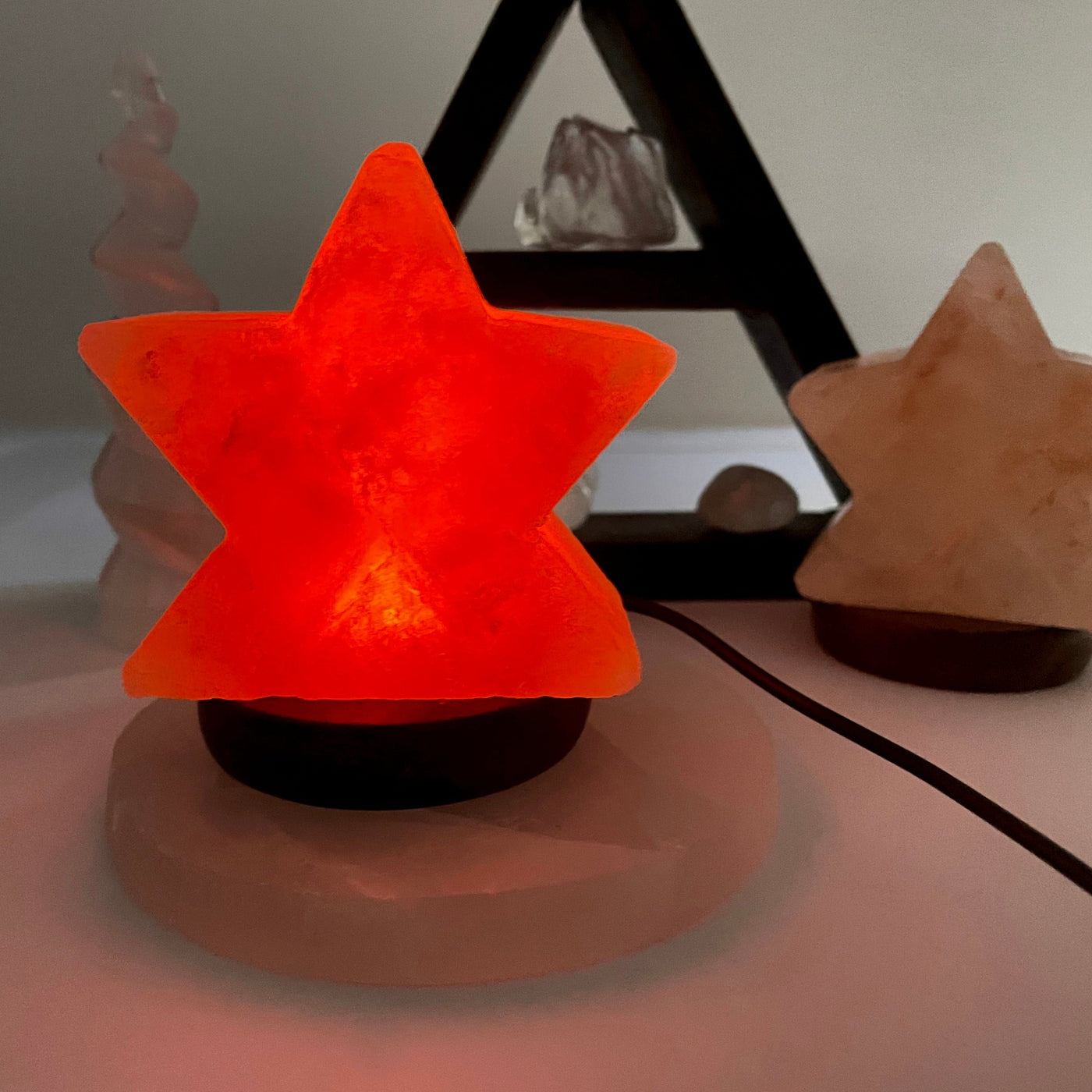 himalayan salt orange star lamp turned on in the dark in front of backdrop