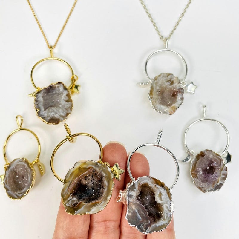 agate geode pendants with moon and star charms in hand for size reference 