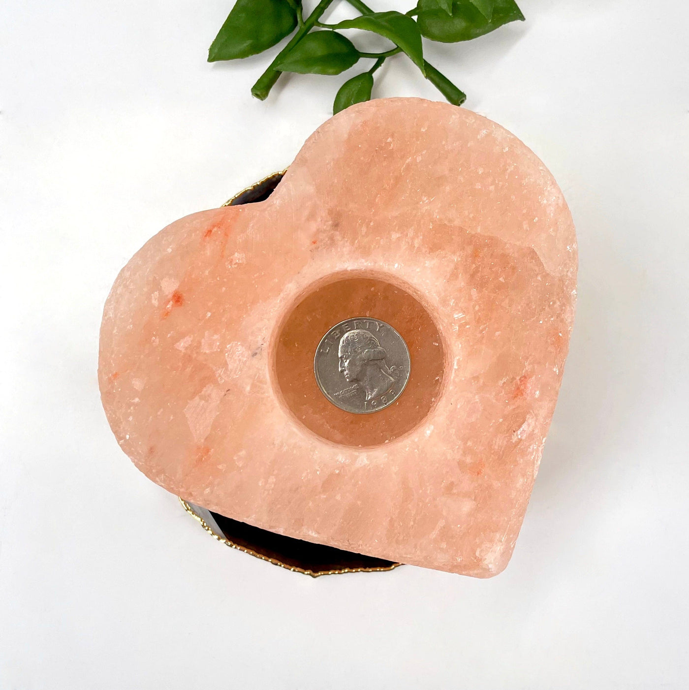 overhead view of one himlayan salt orange heart candle holder with quarter for size reference