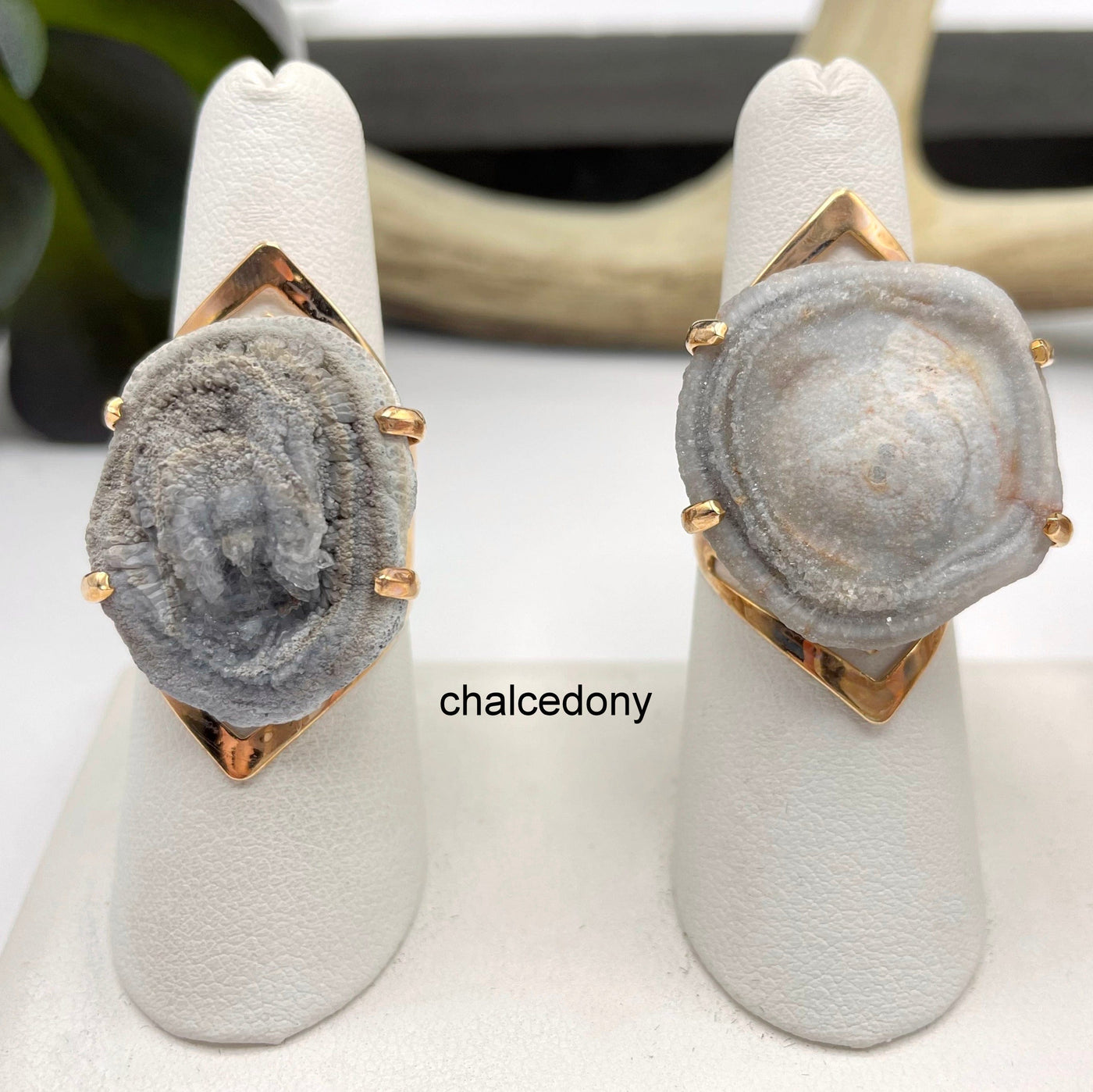 close up of two chalcedony druzy rings on ring display in front of backdrop for details and possible variations