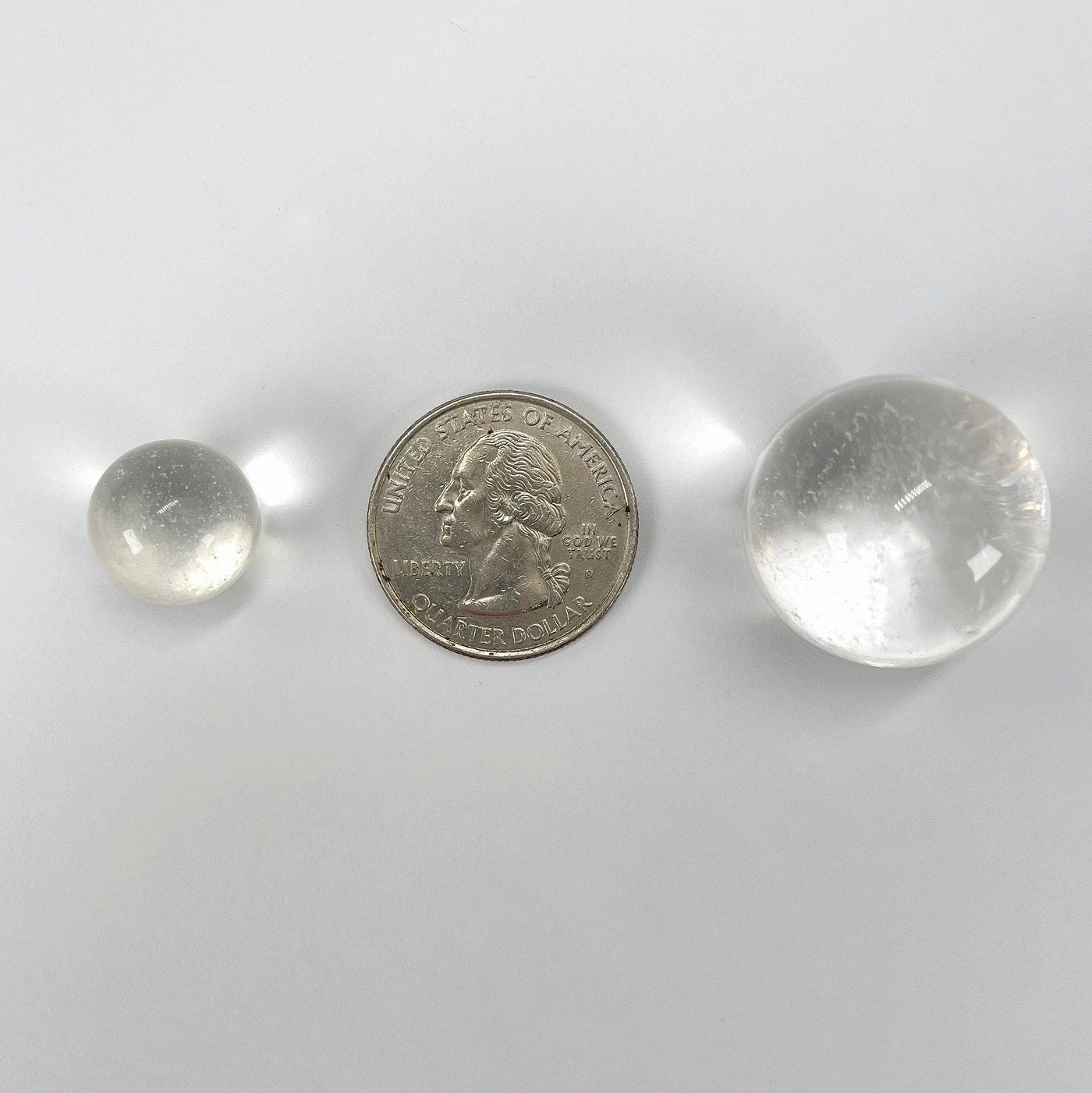 close up of approximate smallest and largest crystal quartz spheres with quarter for size reference
