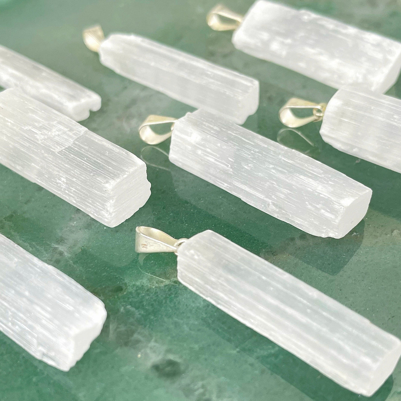 angled view of many selenite rough pendants for thickness
