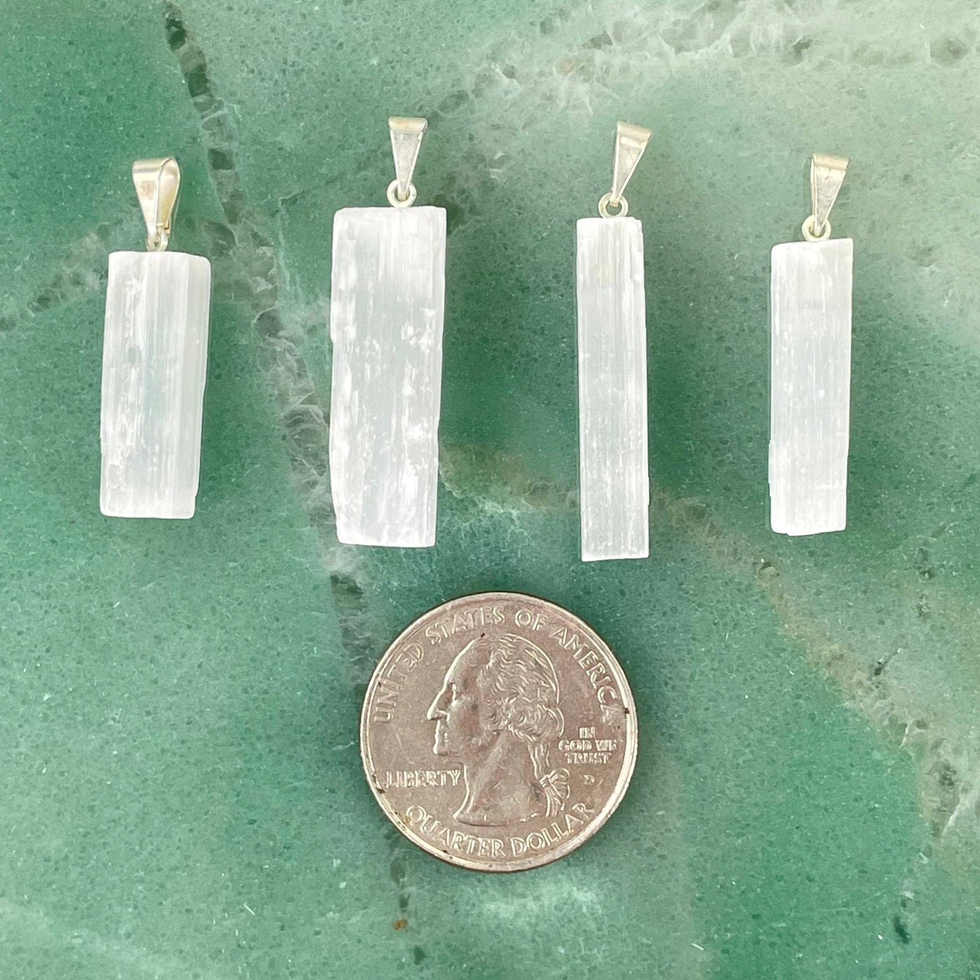 four selenite rough pendants with quarter for size reference