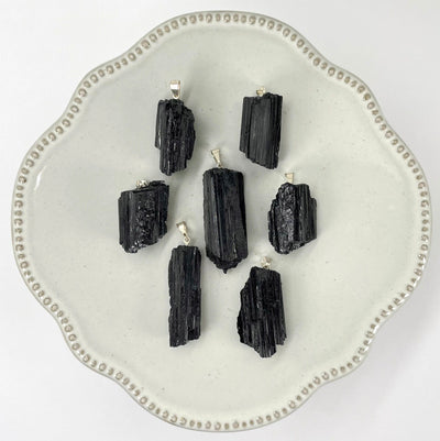 many black tourmaline rough pendants on display for possible variations