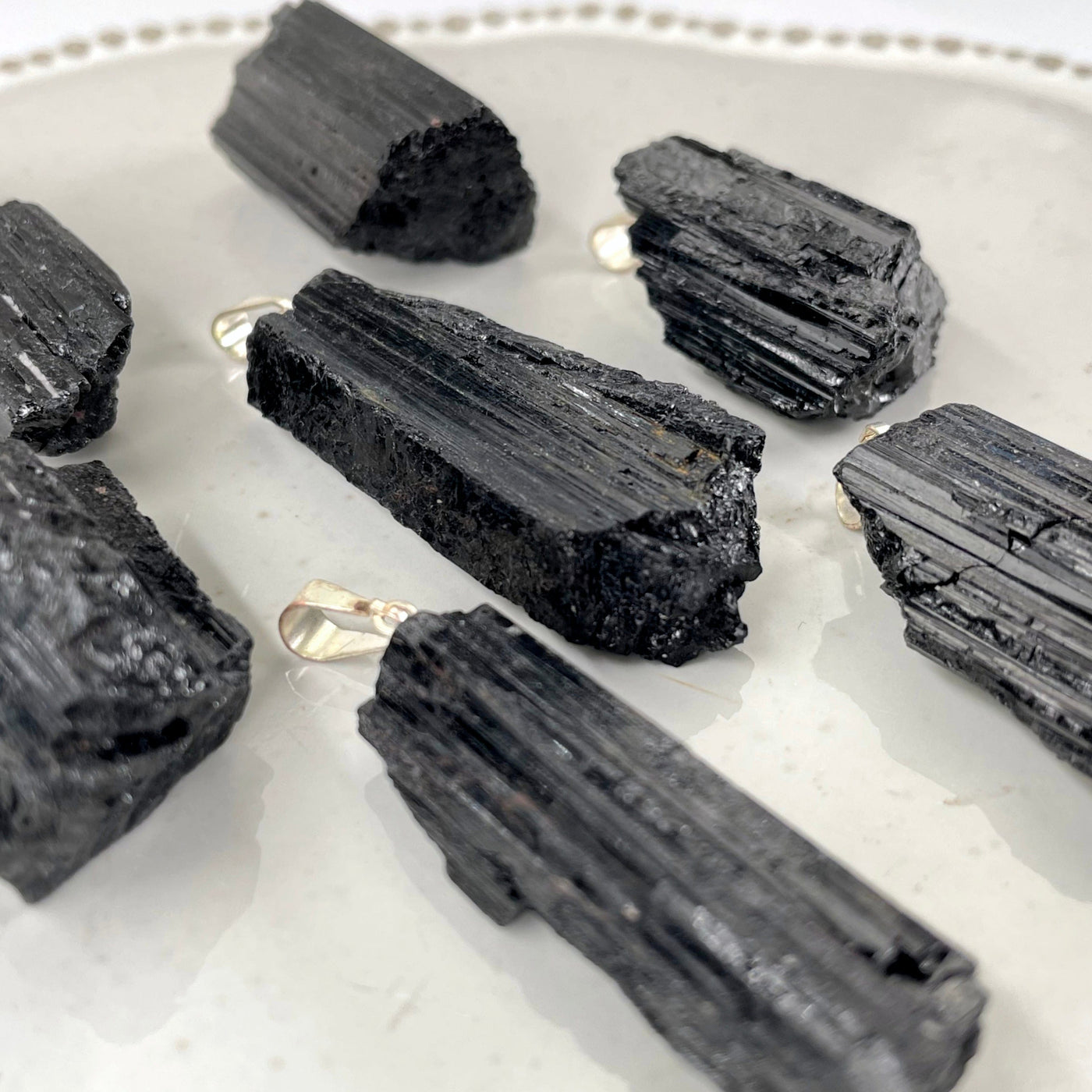 angled view of many black tourmaline rough pendants on display for thickness