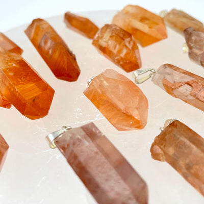angled view of many tangerine rough point pendants for thickness