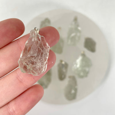 close up of prasiolite rough pendant in hand for size reference with others in background