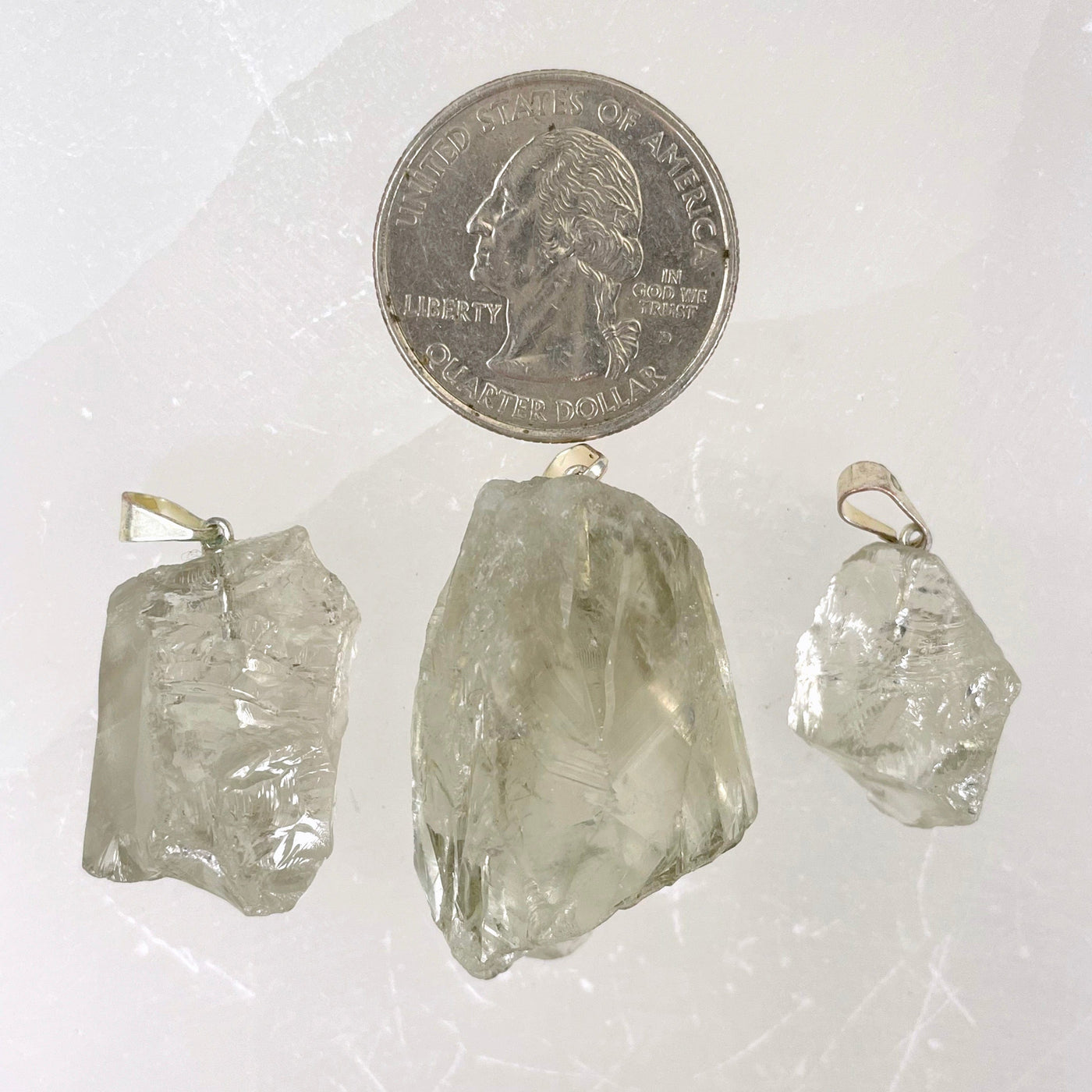 three prasiolite rough pendants with quarter for size reference