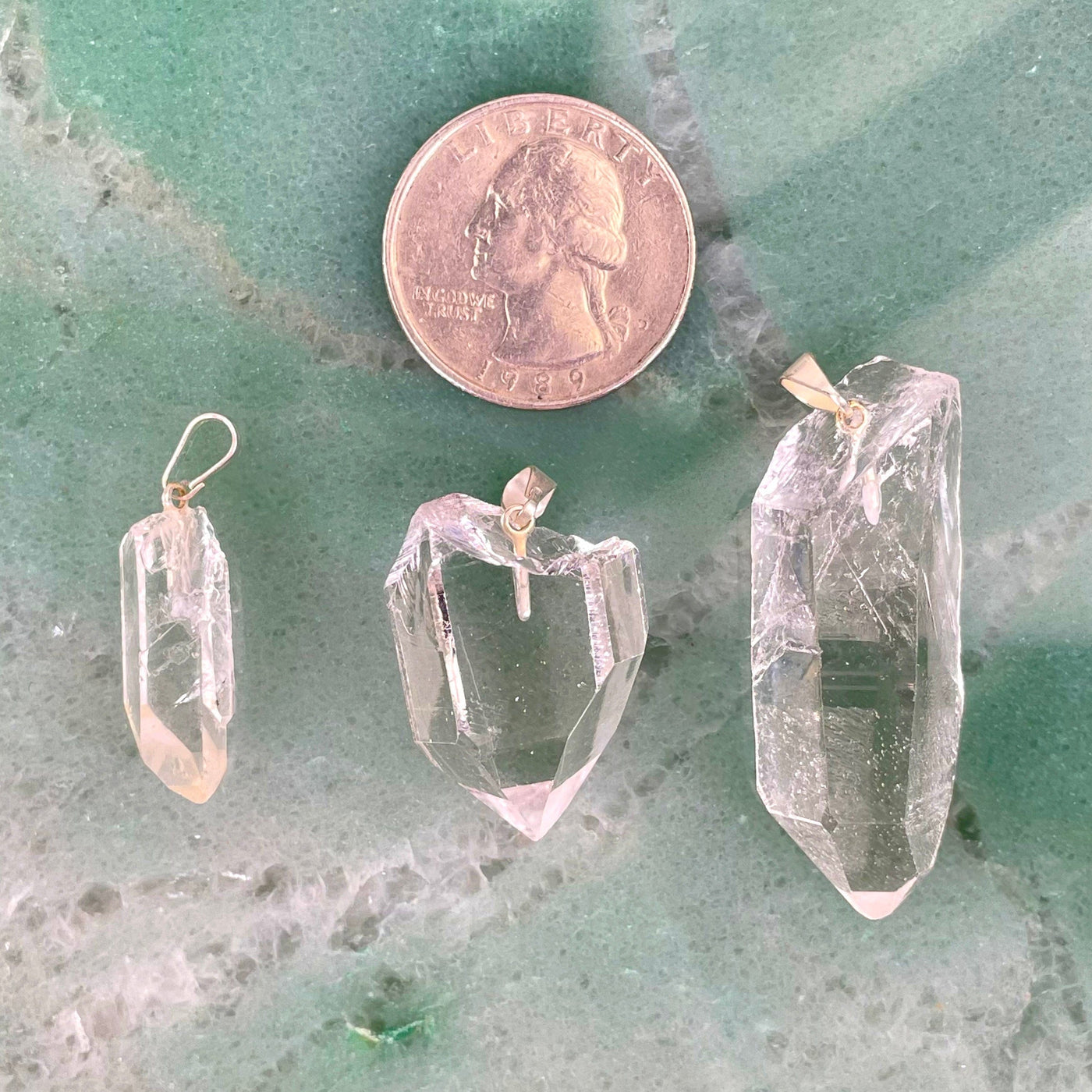 three crystal quartz rough point pendants with quarter for size reference