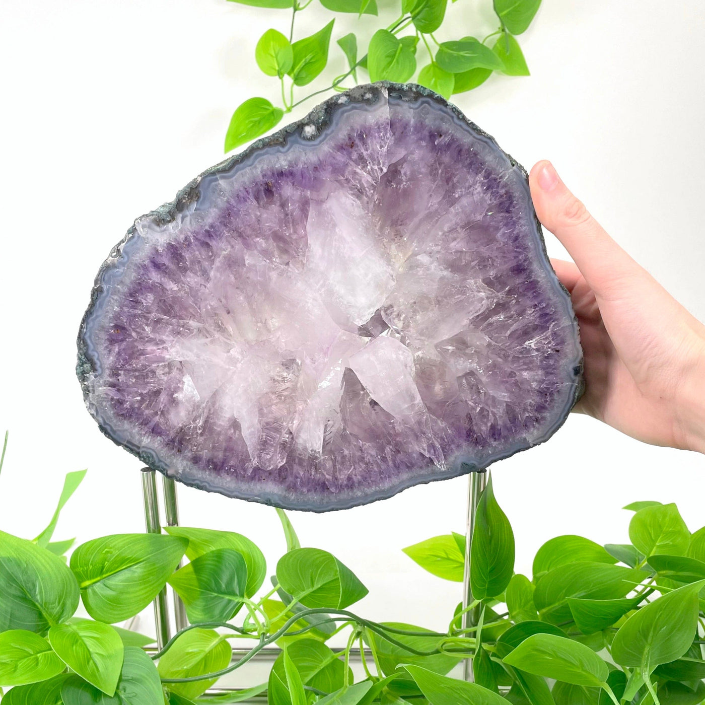 large amethyst slab on stand with hand for size reference
