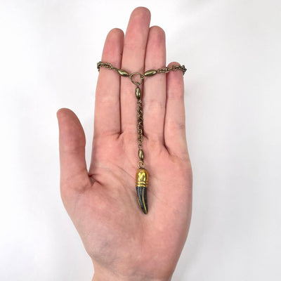 tibetan style gold and black horn pendant in hand for size reference