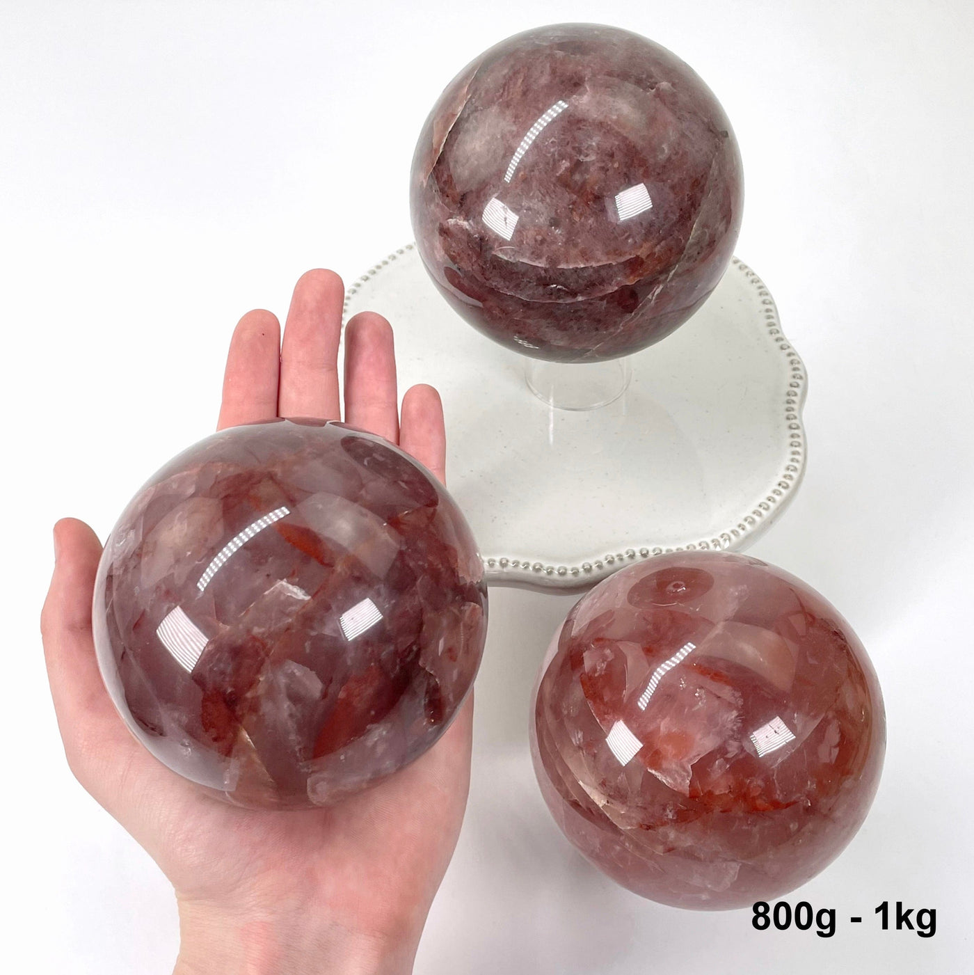 one 800g - 1kg guava polished sphere in hand with two others on display for possible variations