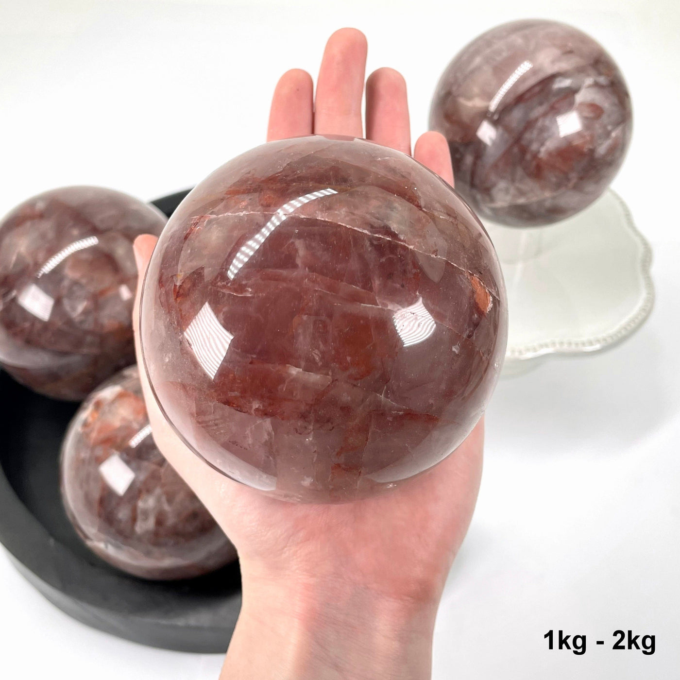 one 1kg - 2kg guava polished sphere in hand for size reference with others in background display
