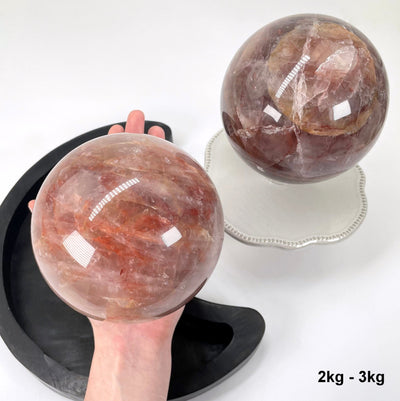 one 2kg - 3kg guava polished sphere in hand with one other for possible variations