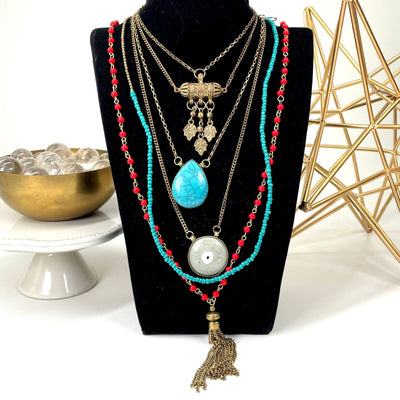 five tier beaded pendant necklace on bust display in front of backdrop