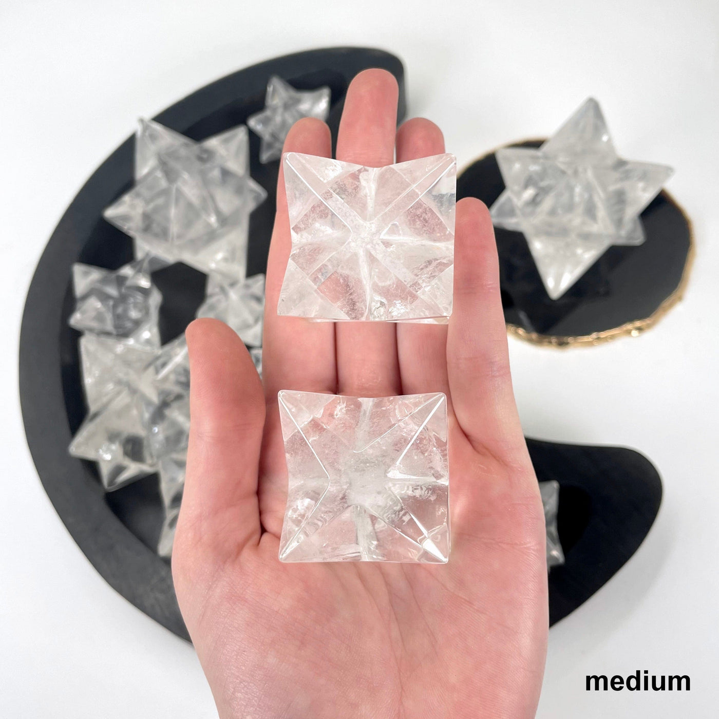 two medium crystal quartz merkabah stars in hand for size reference and possible variations with others in background display