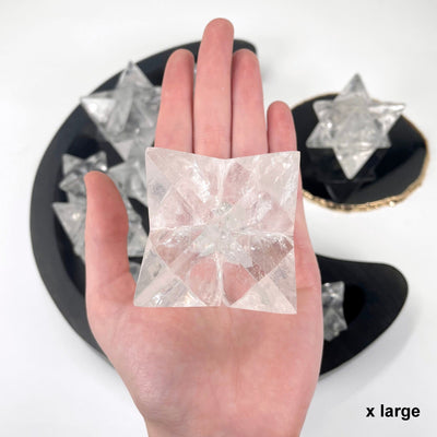 one x large crystal quartz merkabah star in hand for size reference with others in background display