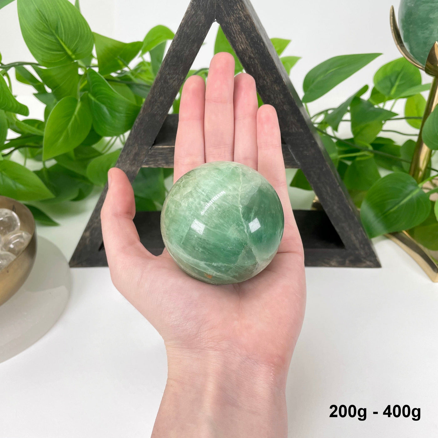 one 200g - 400g green fluorite sphere in hand for size reference