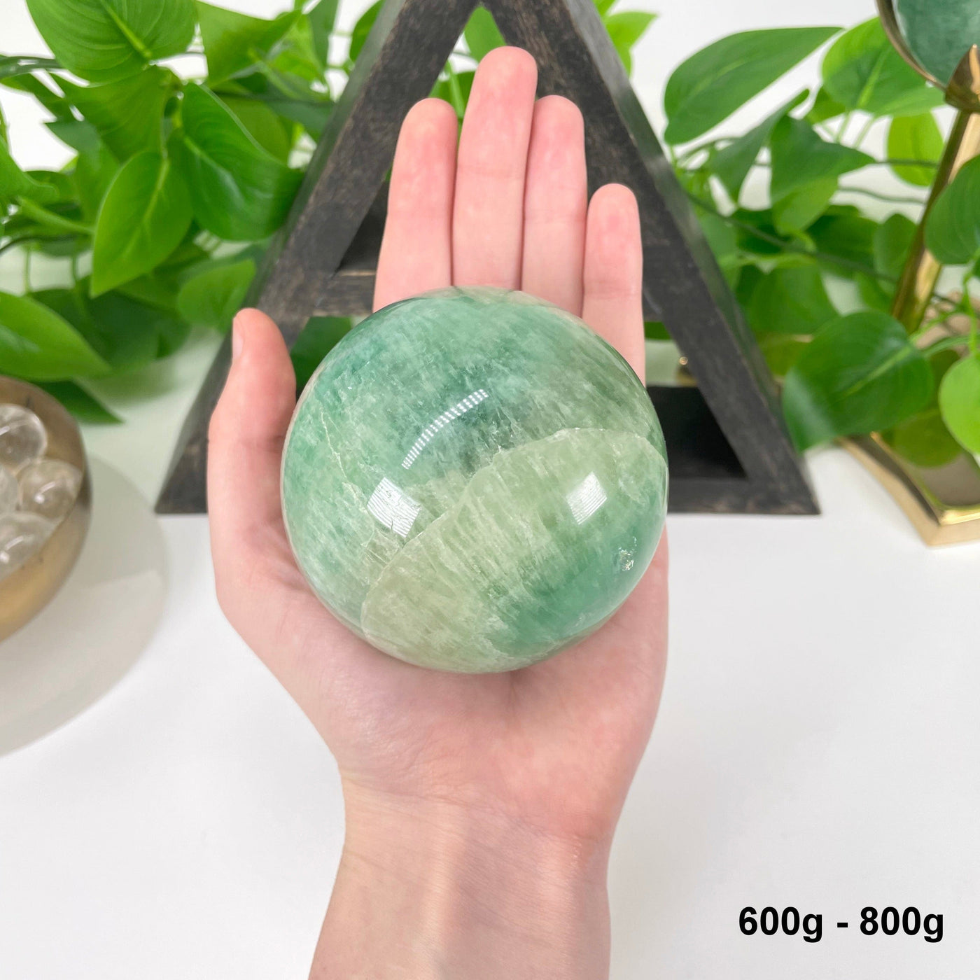 one 600g - 800g green fluorite sphere in hand for size reference
