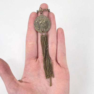 close up of large coin with gold tassel in hand for size reference and details
