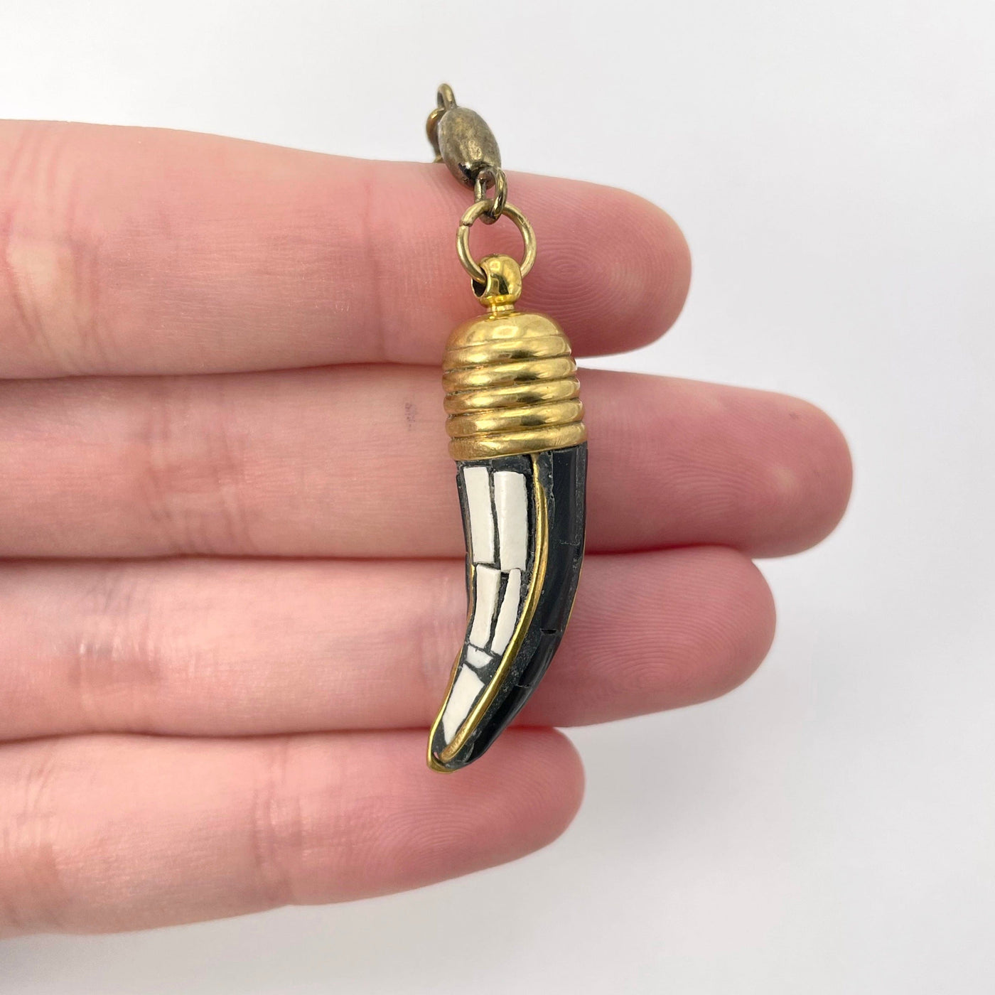 close up of black and white horn pendant in hand for size reference and details