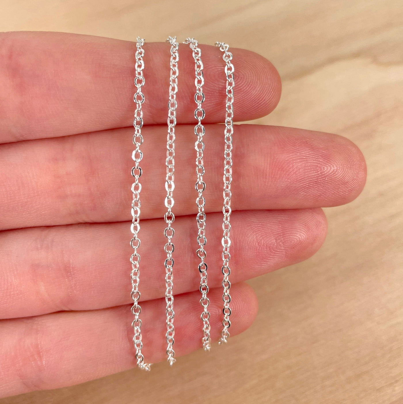 close up of electroplated silver necklace chain in hand for size reference and details