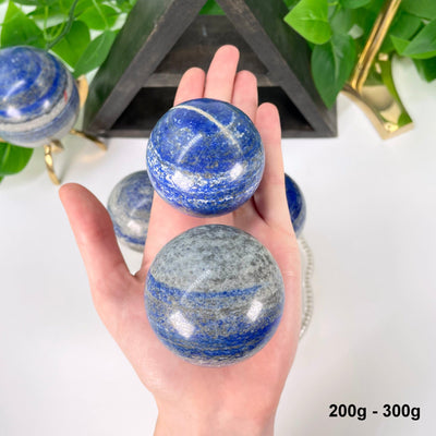 two 200g - 300g lapis lazuli polished spheres in hand 