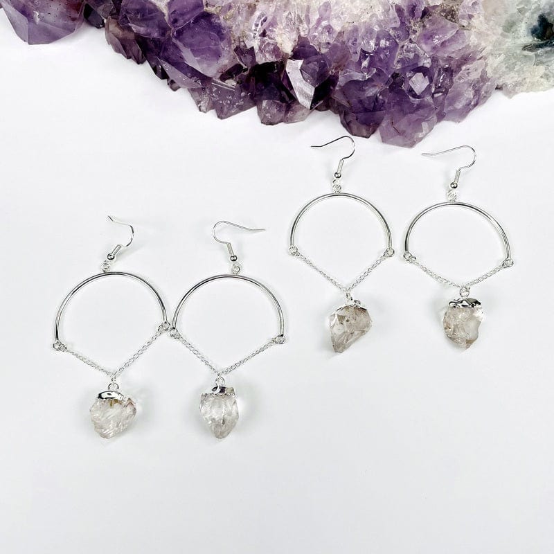 two pairs of crystal quartz fancy dangle earrings displayed to show the differences in the crystal sizes 