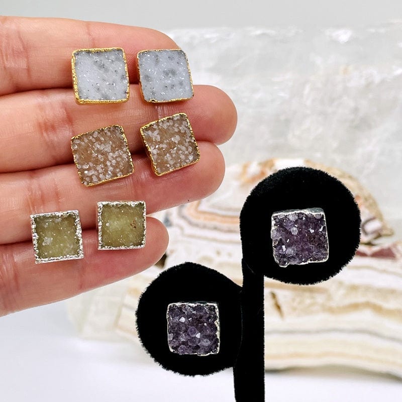 multiple earring pairs in hand to show the differences in the druzy types