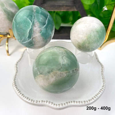 three 200g - 400g green and white quartz spheres on display for possible variations 