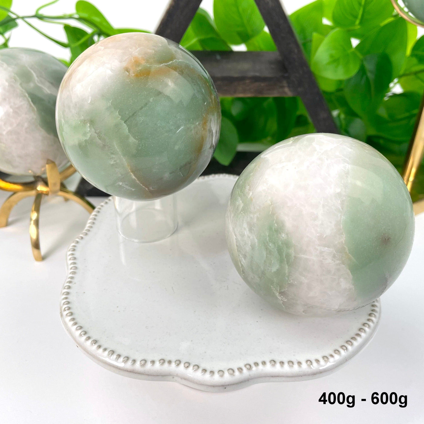 two 400g - 600g green and white quartz spheres on display for possible variations