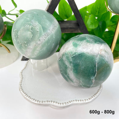 two 600g - 800g green and white quartz spheres on display for possible variations