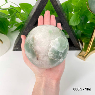 one 800g - 1kg green and white quartz sphere in hand for size reference