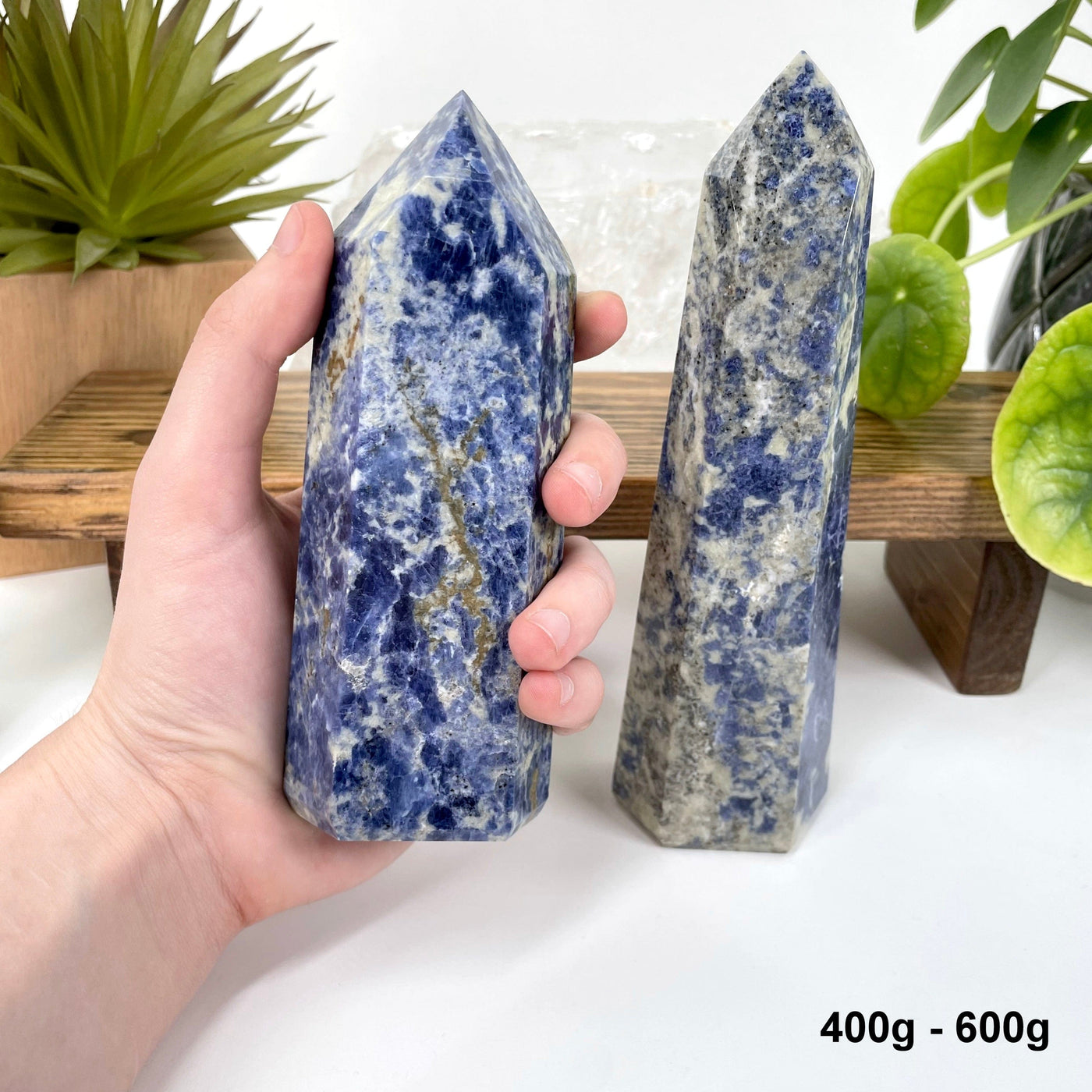 one 400g - 600g sodalite polished point in hand for size reference with one other on display for possible variations
