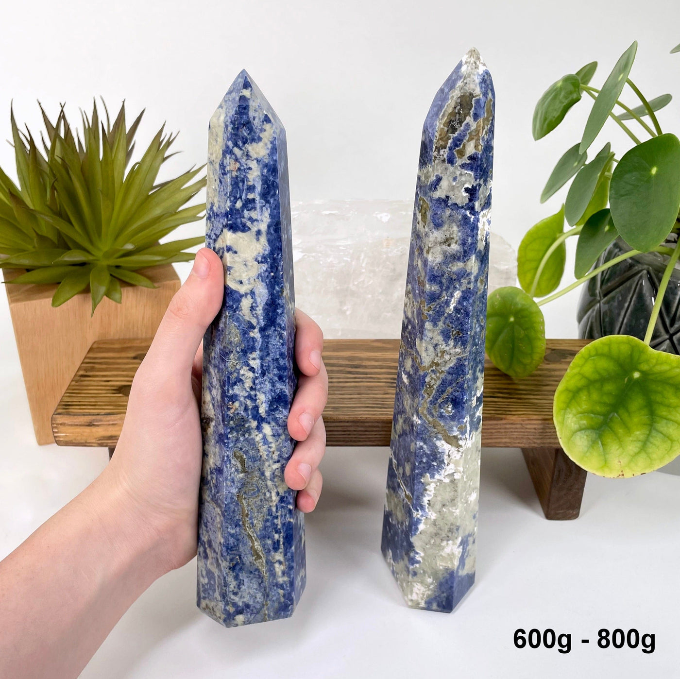 one 600g - 800g sodalite polished point in hand for size reference with one other on display for possible variations